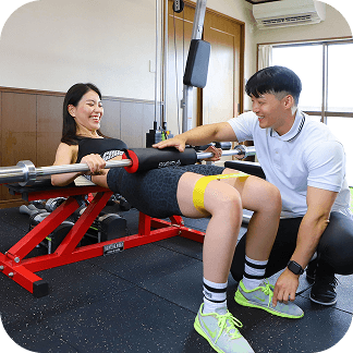 トレーナーの指導のもとトレーニングマシンを使って運動する様子