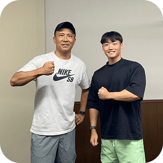 トレーナーと利用者がジム内で並んでポーズを取っている様子